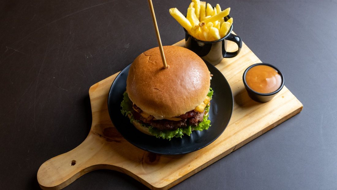 Burger et frites servis sur une planche avec une sauce à part