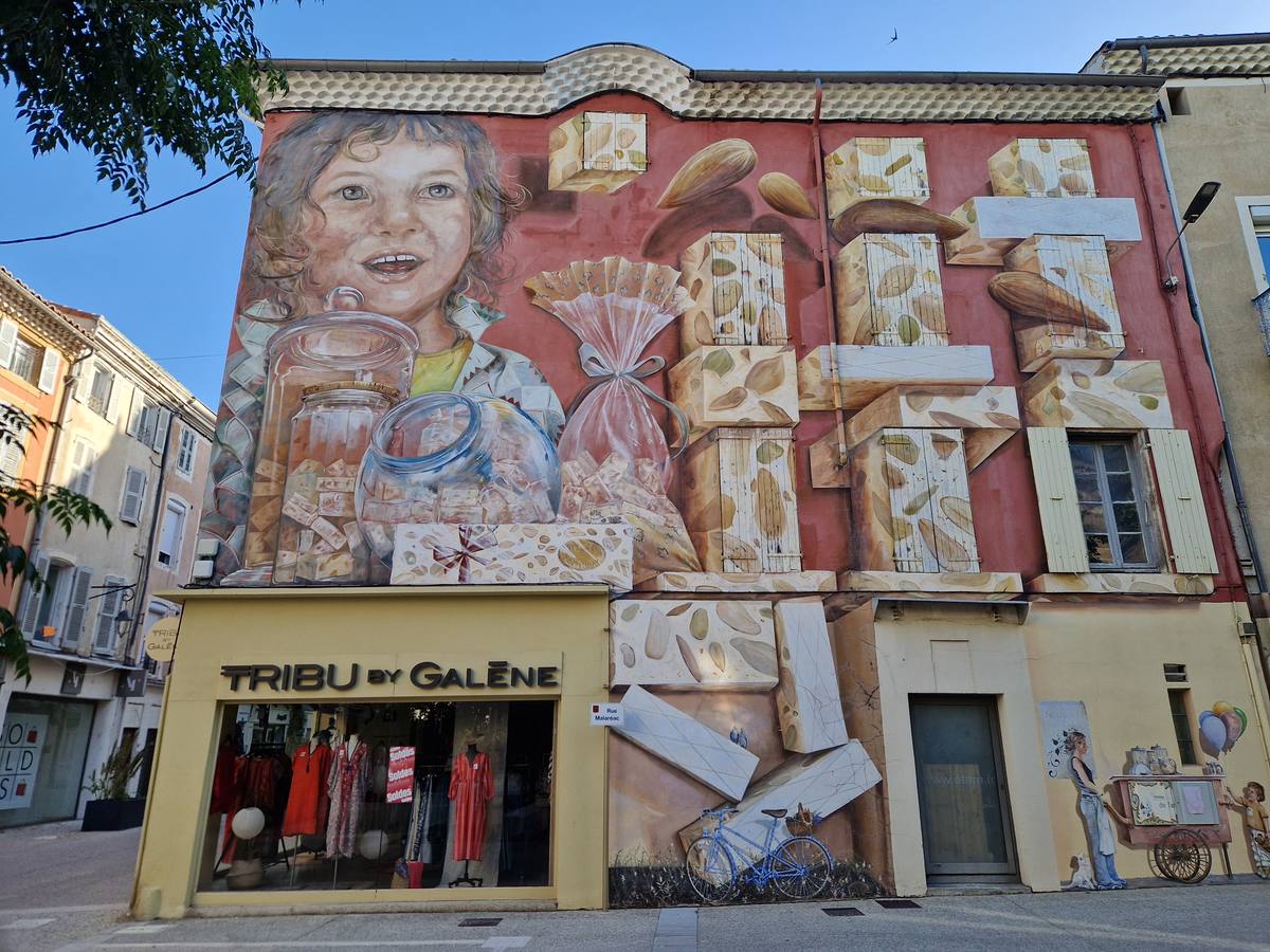 Une grande fresque sur une façade du centre de Montélimar, un enfant entouré de morceaux de nougat géants