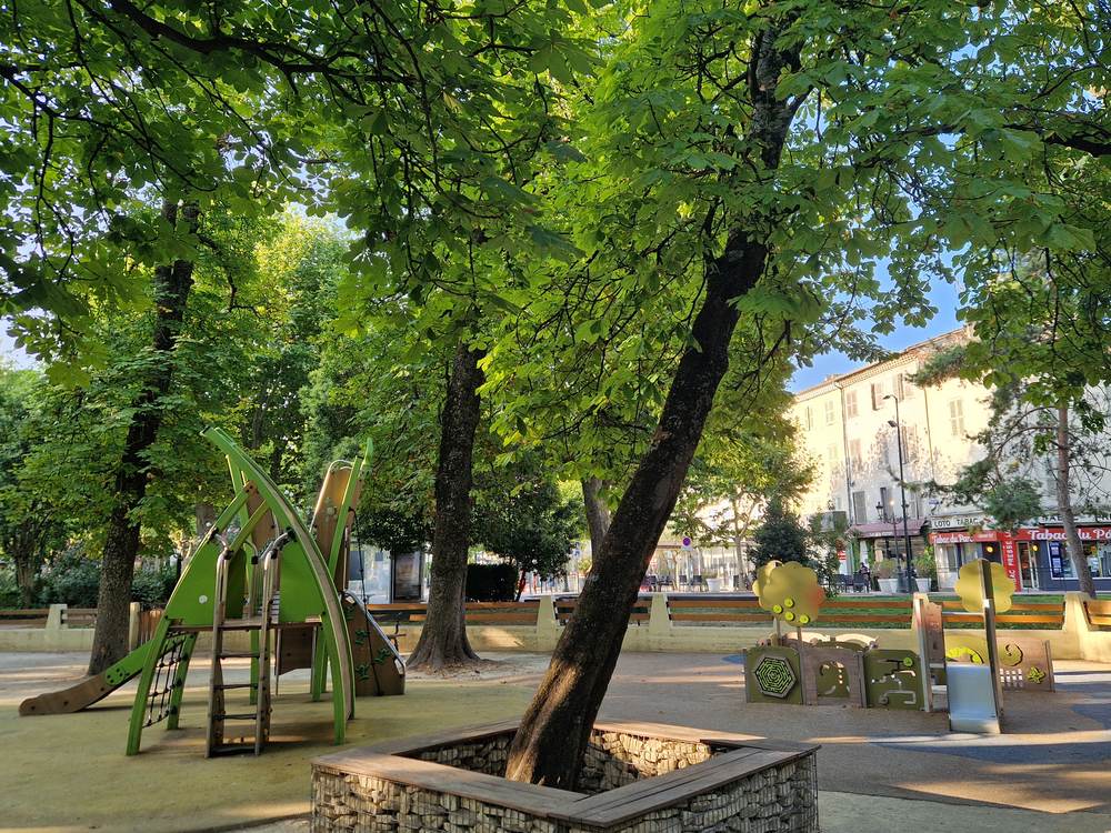 L'aire de jeux du jardin public de Montélimar, toboggans verts sous de grands arbres