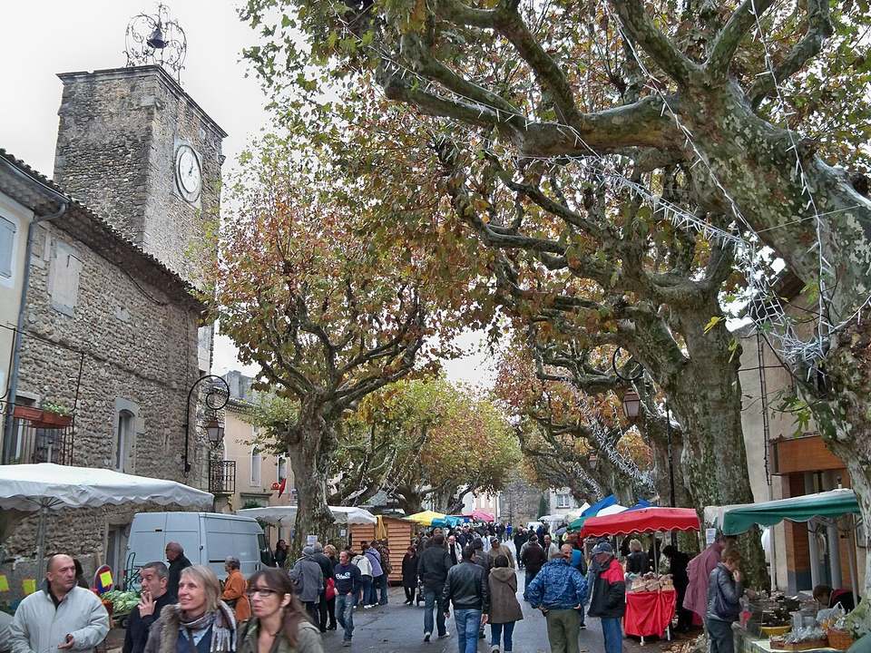 Le cours planté de platanes de Richerenches un samedi de marché aux truffes, avec la tour de l'horloge et les étals