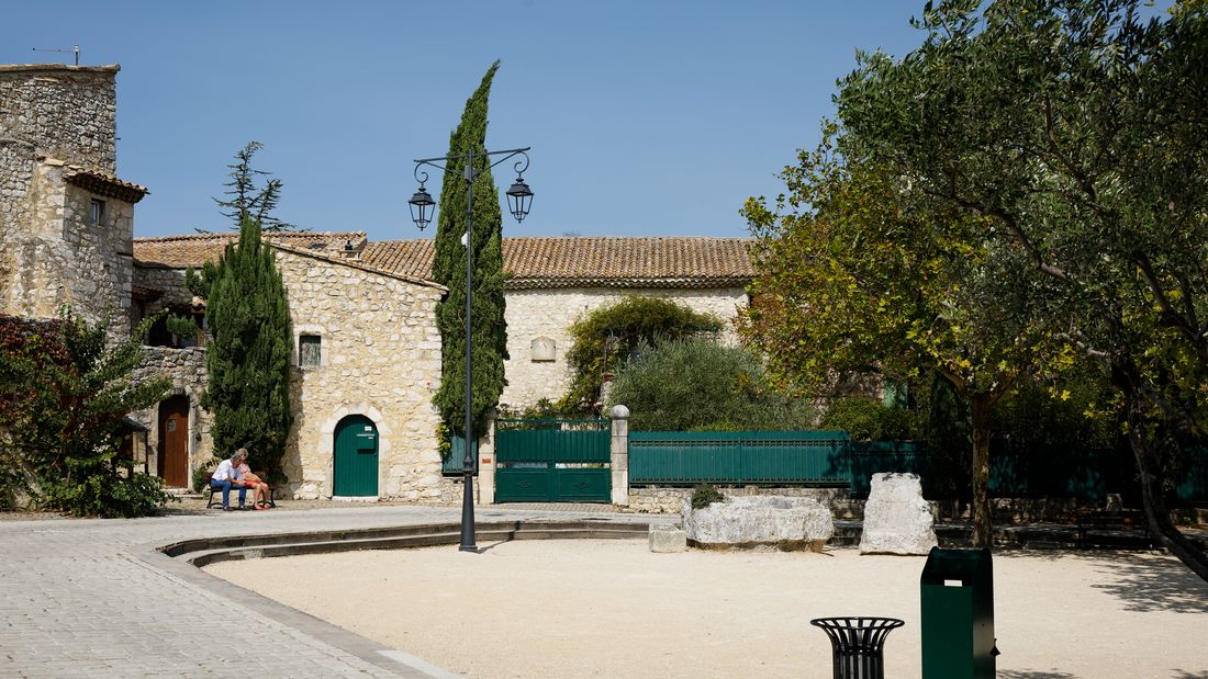 Place de la Loge à La Garde-Adhémar, maisons en pierre claire et cyprès