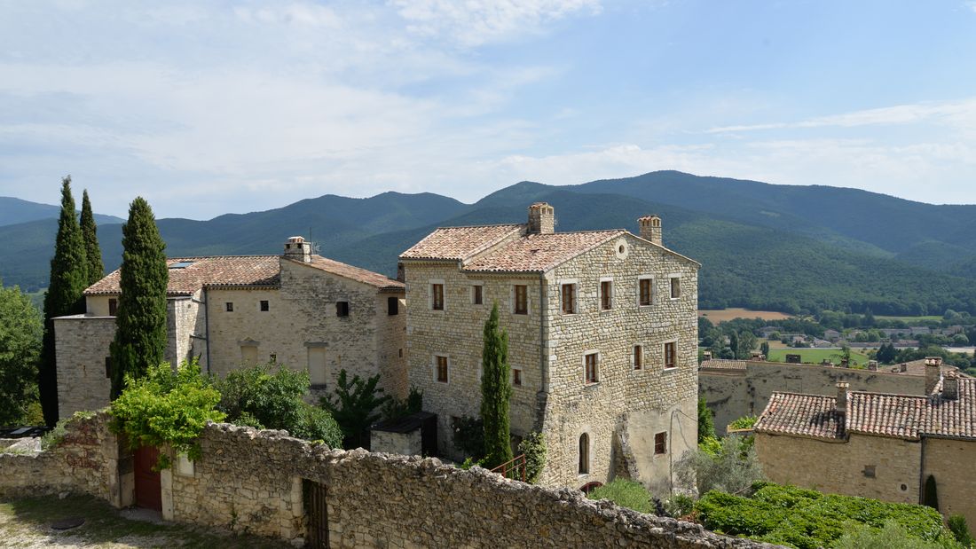 Le vieux village du Poët-Laval accroché à sa colline, maisons de pierre et cyprès